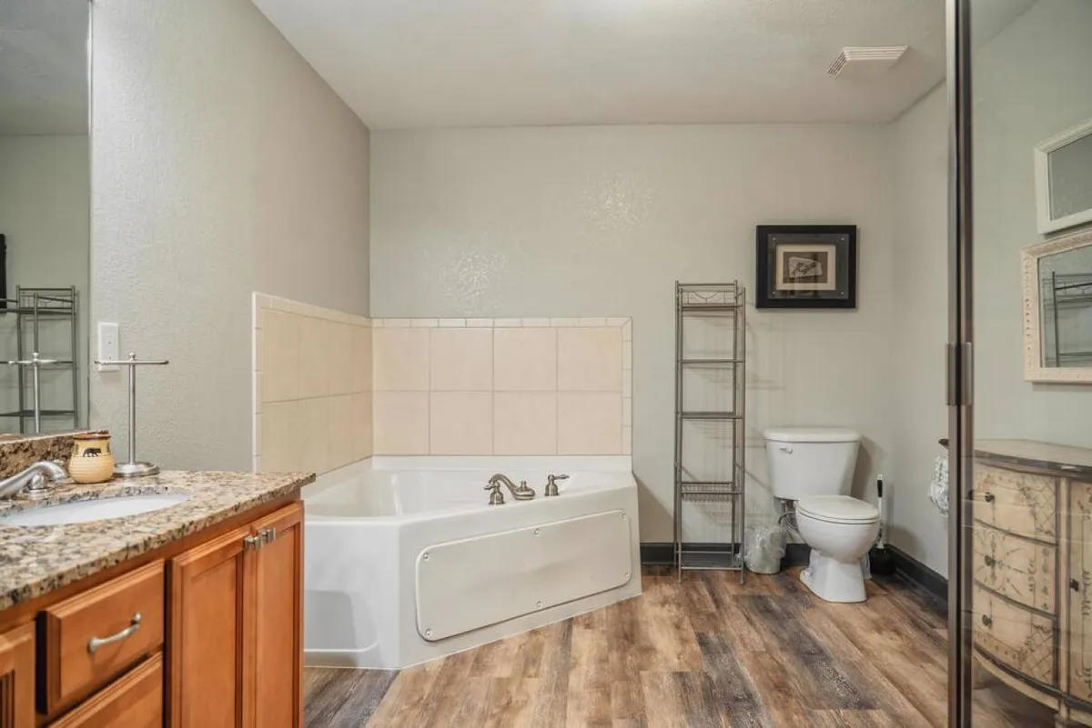 A serene en suite bathroom featuring a prominent bathtub, a well-appointed vanity with sink, towel storage, and a toilet. The layout feels both functional and pampering, evoking a spa-like atmosphere for relaxation.