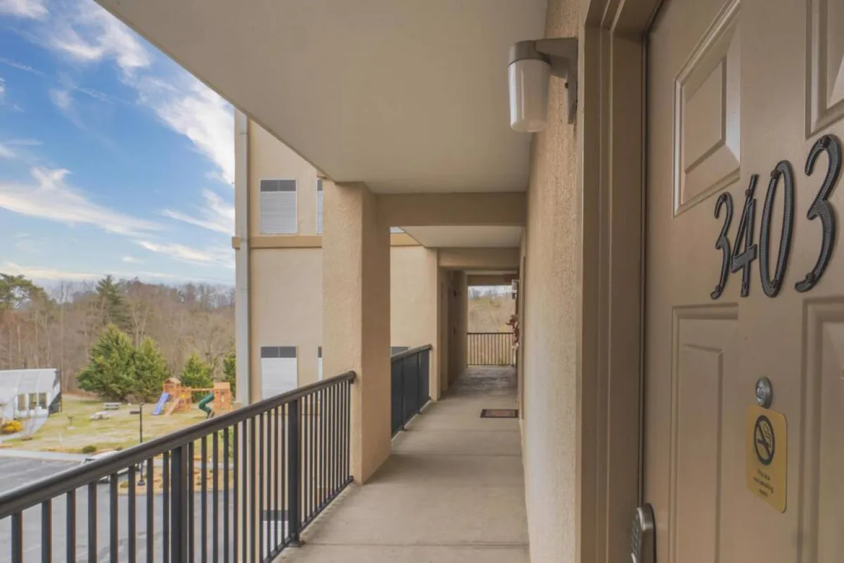 A welcoming condo entrance with door number 3403, bordered by a railing and offering glimpses of the surrounding landscape. The scene suggests a friendly, communal atmosphere, ideal for groups gathering after experiencing local entertainment.