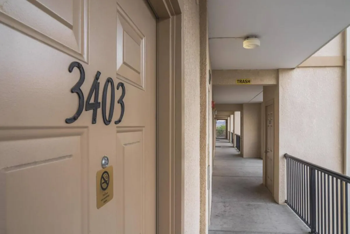 A calm corridor scene at Mountain View Condos, featuring the entrance to unit 3403, a light fixture overhead, and doors leading to other apartments. The image conveys a sense of arrival and hints at the building's welcoming communal areas.