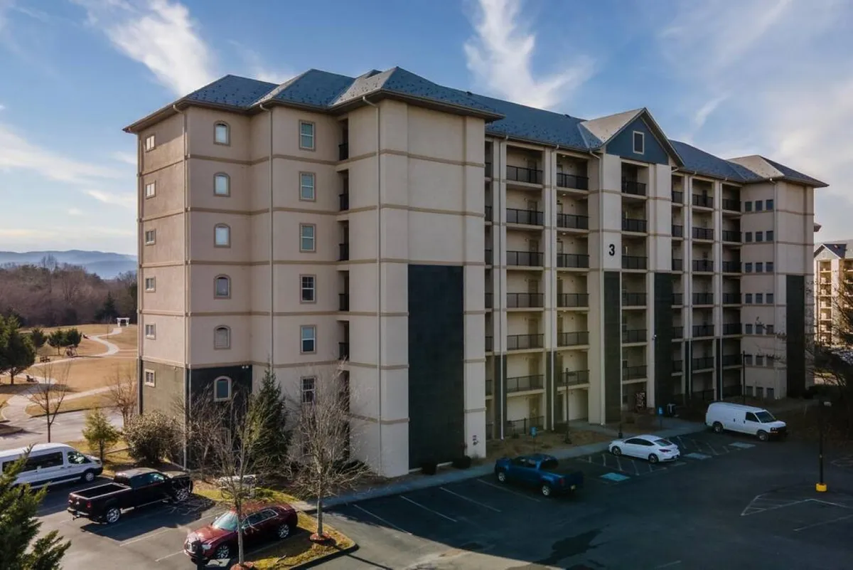 An inviting view of the building's facade, framed by attractive landscaping and a convenient parking lot. The scene suggests a welcoming entry with easy access and a vibrant community atmosphere, all set amidst natural beauty.